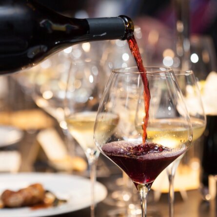 waitress pour red wine in the glass on the table in restaurant